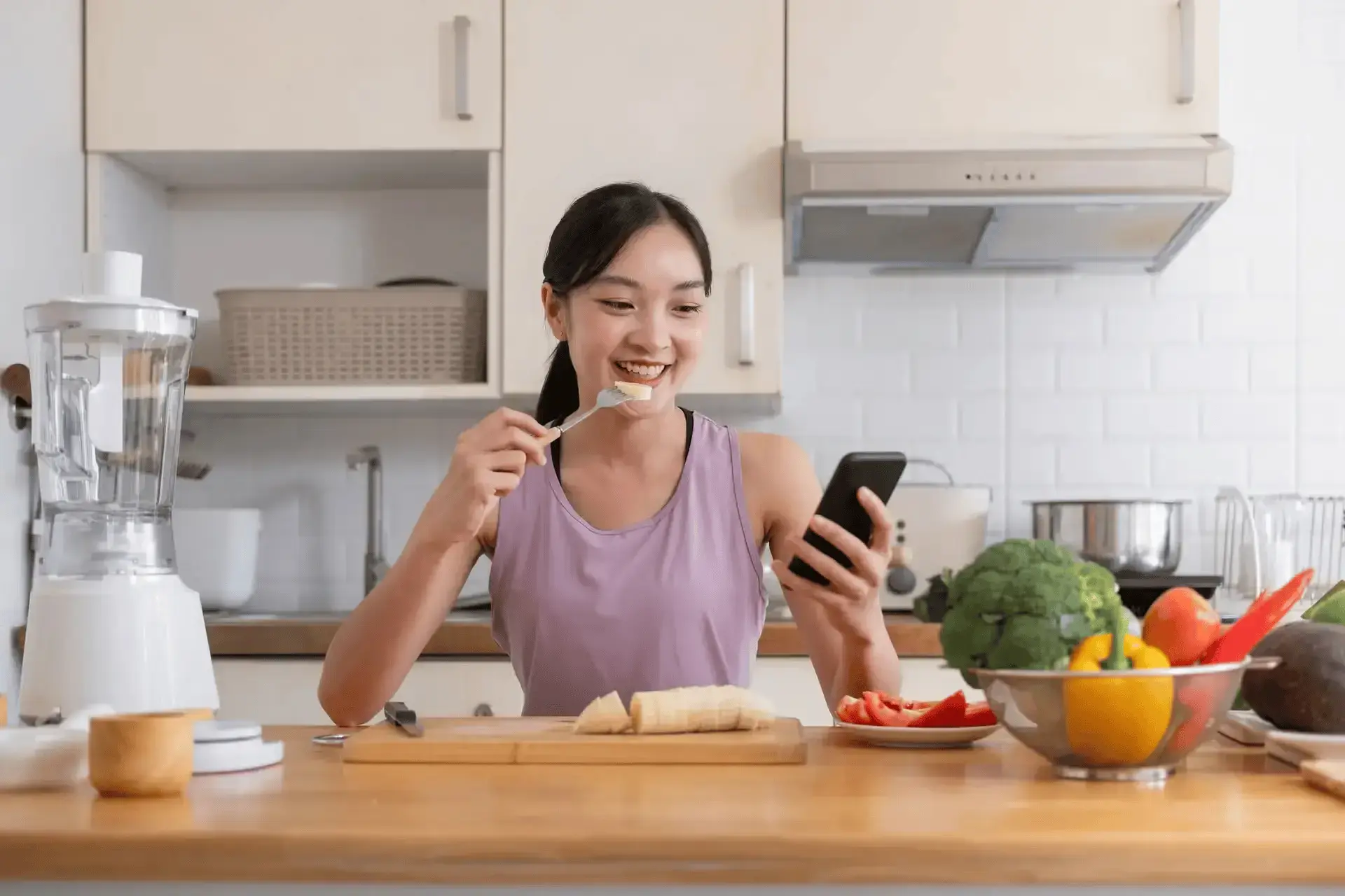 A woman enjoying a slice of banana while looking at her phone