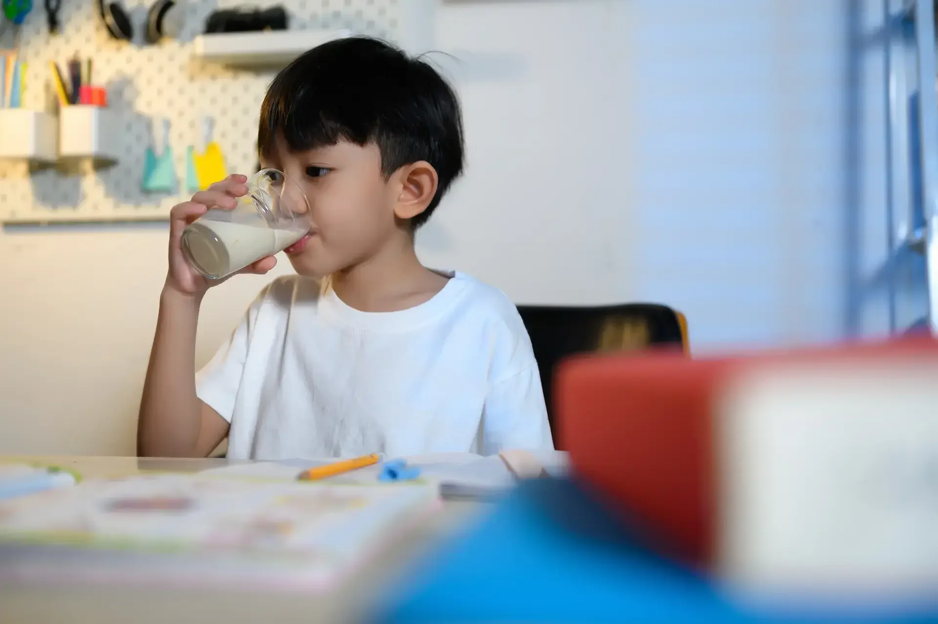 Batang umiinom ng gatas habang nagbabasa ng aklat.