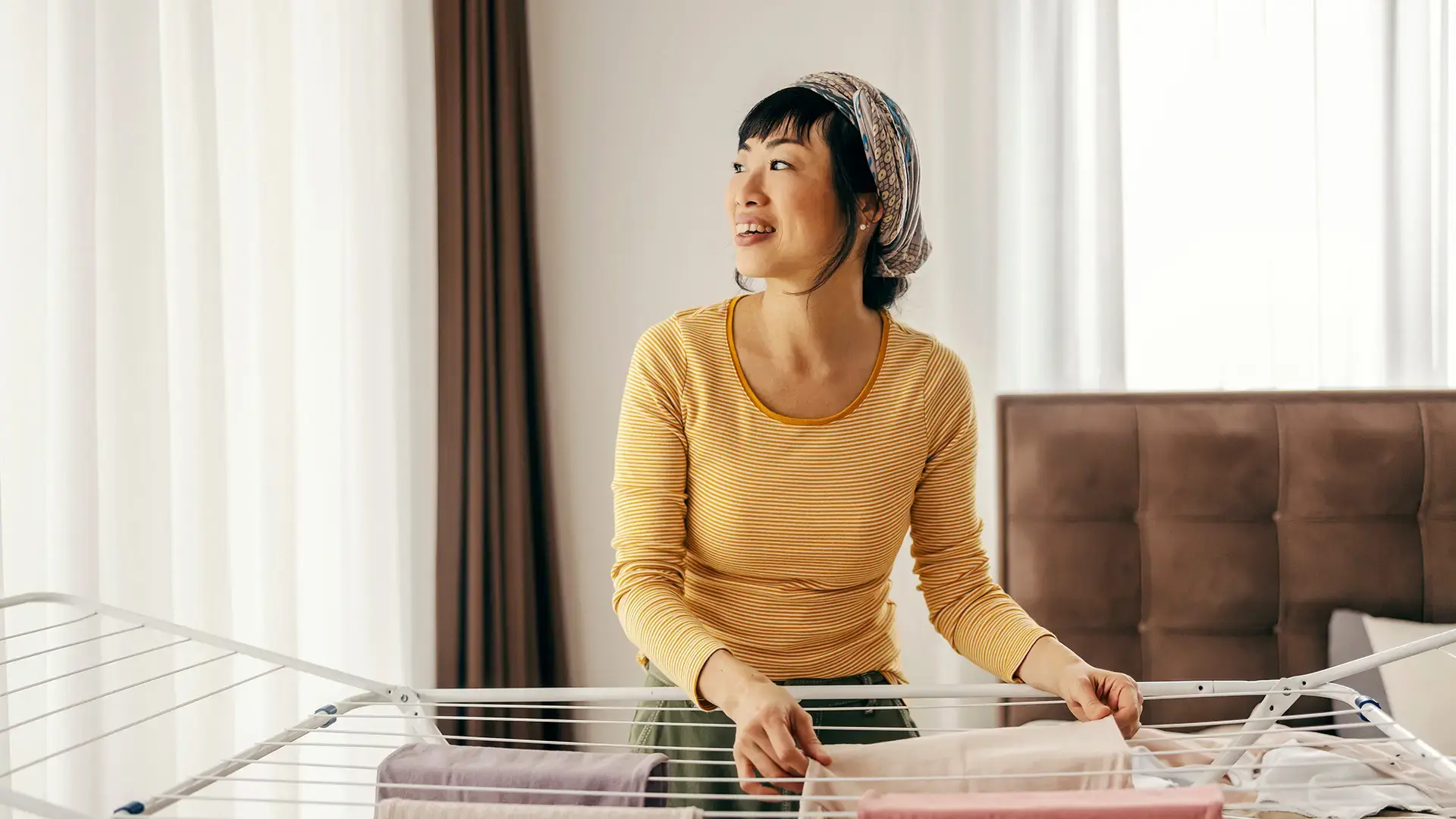 A happy japanese housewife is doing chores and doing laundry at home