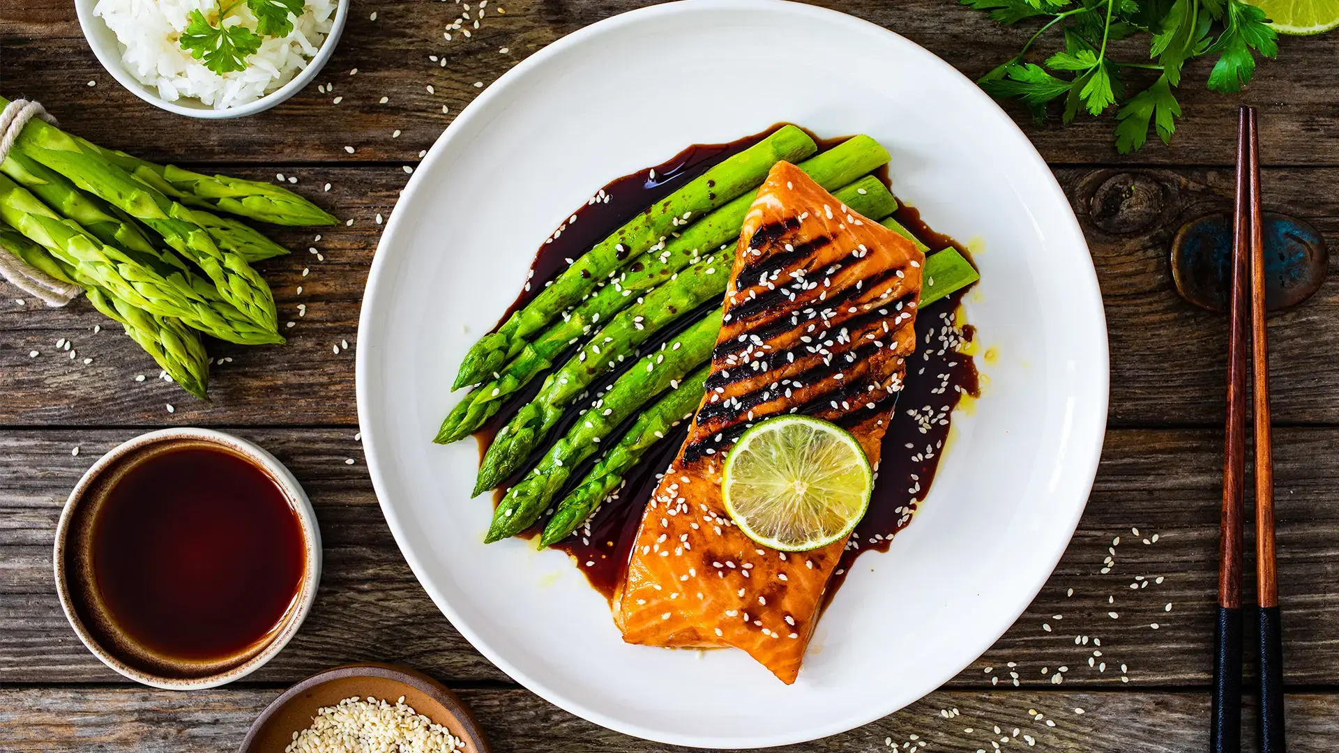 Grilled salmon steak with green asparagus in teriyaki sauce on wooden table
