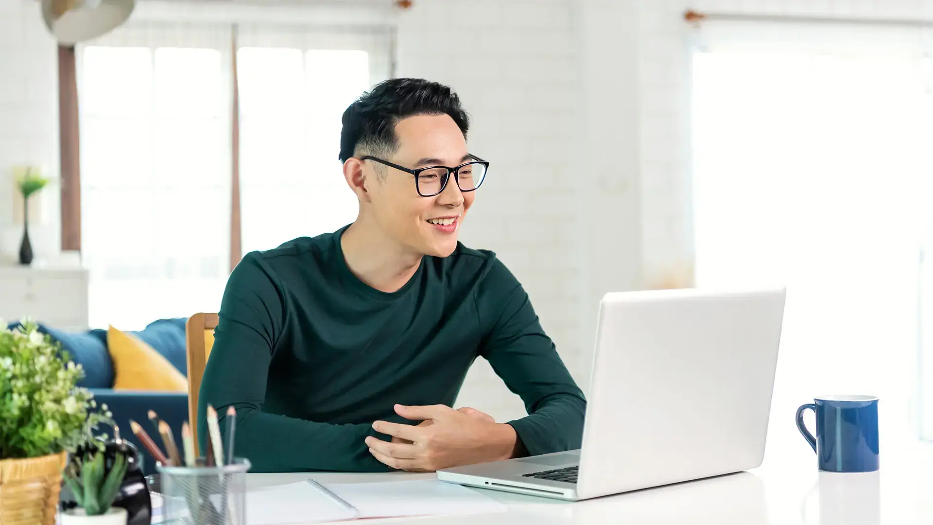 Smiling handsome asian businessman working remotely from home
