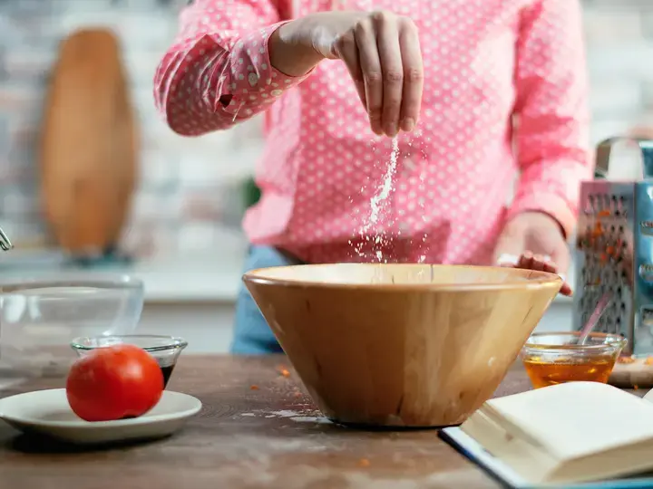 Close-up-of-female-hands-putting-salt-in-food.-Woman-cooking-in-kitchen