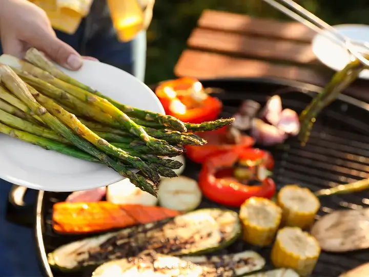 Woman cooking vegetables on barbecue grill outdoors