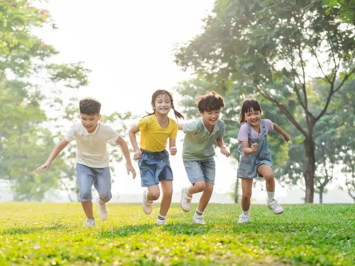 Isang grupo ng mga Asyanong bata na masayang nagtatakbuhan sa parke.