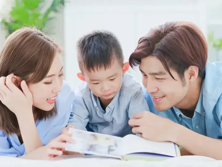 Asyanong pamilya na masayang nagbabasa ng libro.