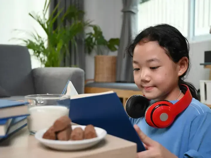 Batang nagbabasa habang umiinom ng gatas.